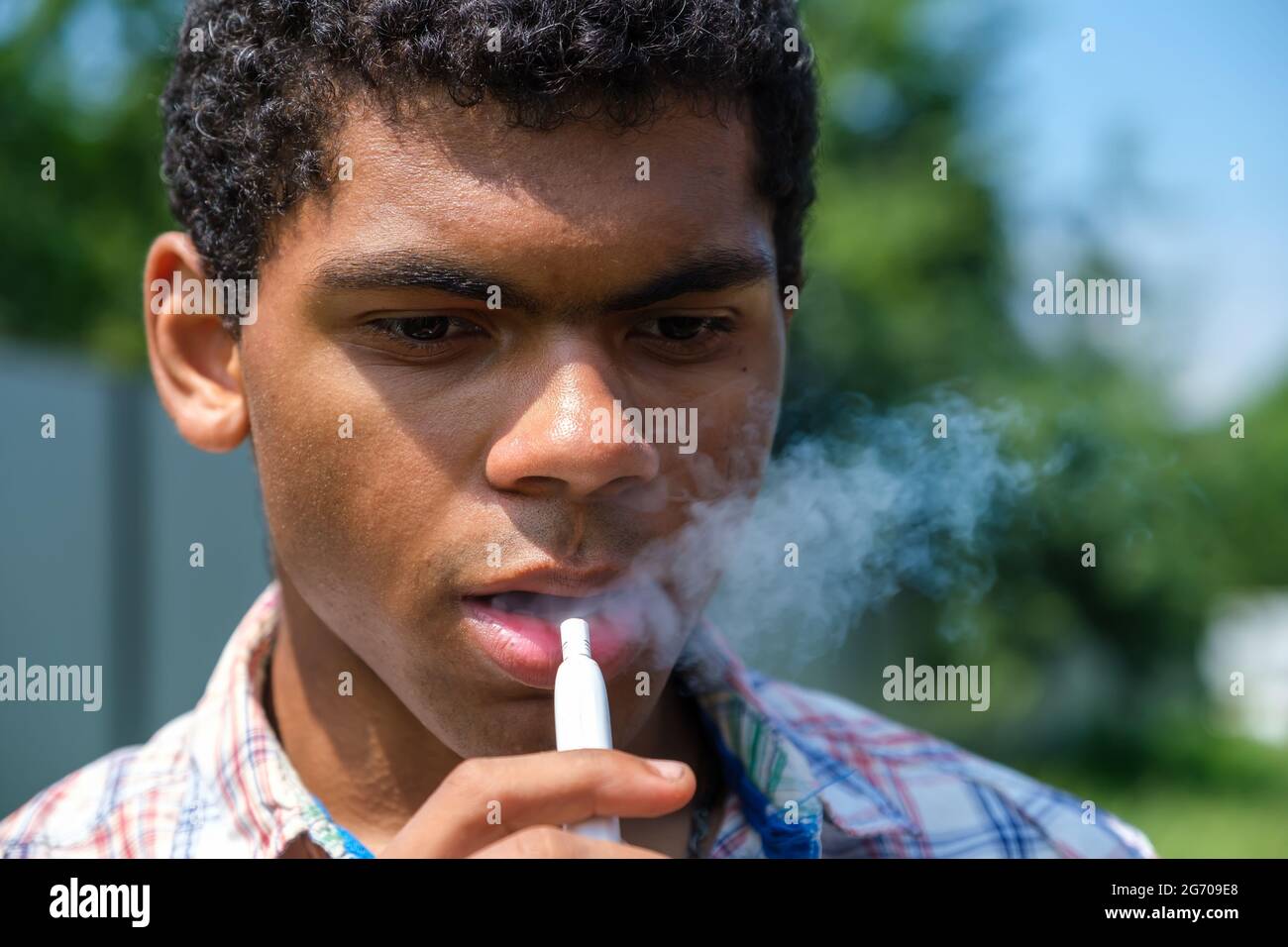 Gros plan brésilien jeune homme vaporing e-cigarette avec e-liquide Photo  Stock