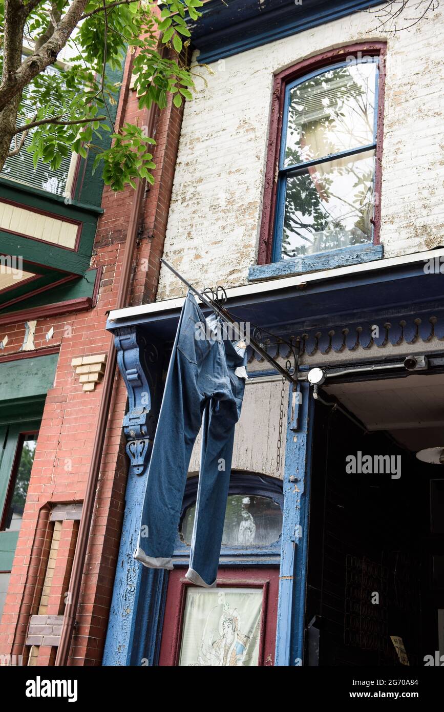 Une grande paire de jeans en denim suspendus pour sécher à partir d'un poteau à l'extérieur d'une vitrine, dans une ville. Banque D'Images