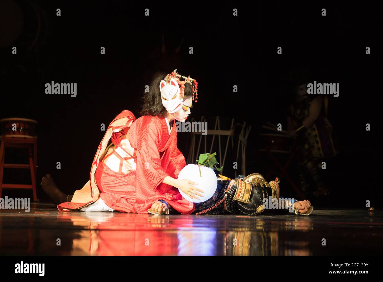 Une japonaise pleure un samouraï mort assis sur ses genoux avec une lampe sur son corps dans l'obscurité. Performances japonaises traditionnelles. Banque D'Images