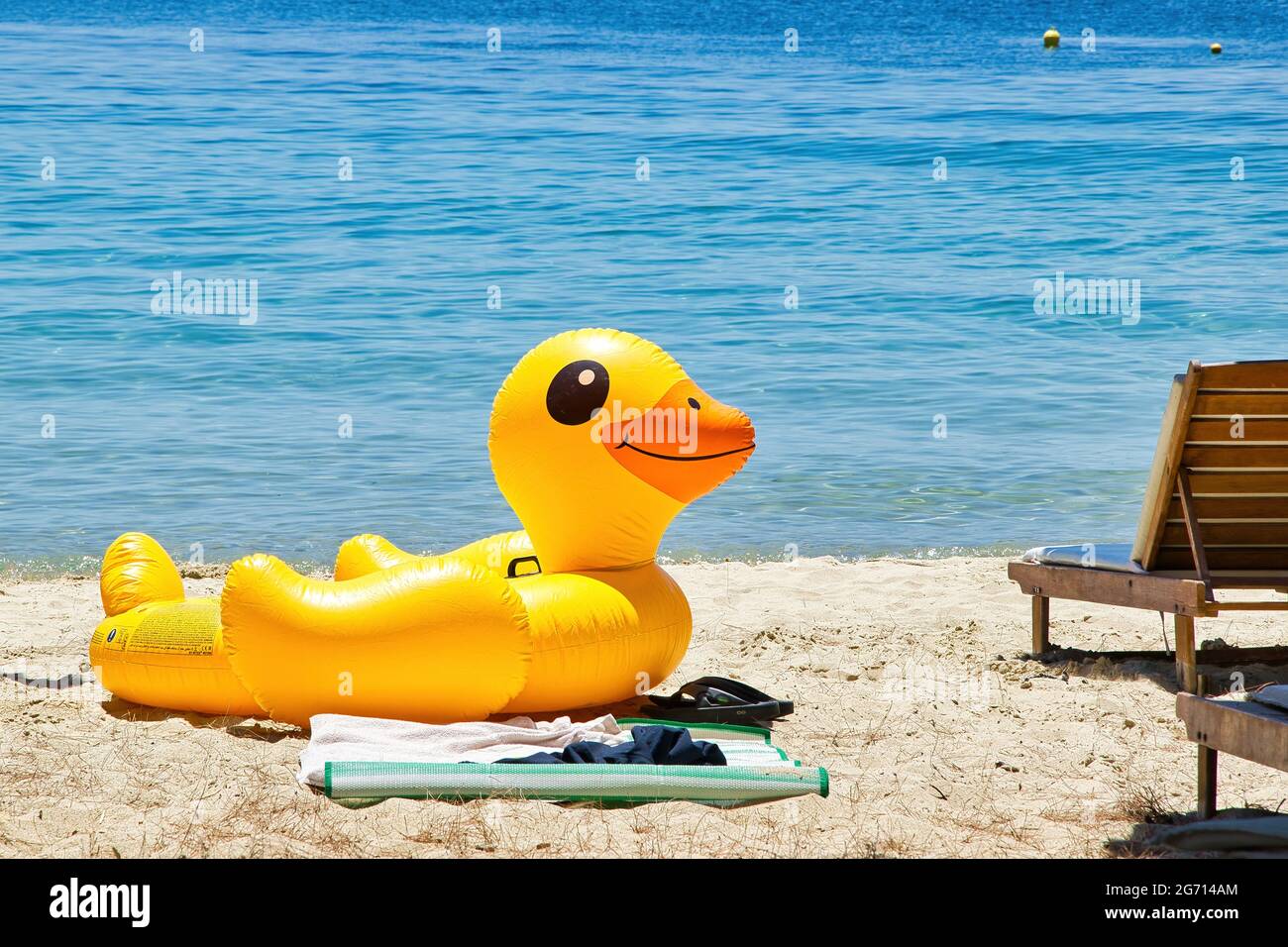 Canard gonflable jaune assis sur la plage en face de la mer. Banque D'Images