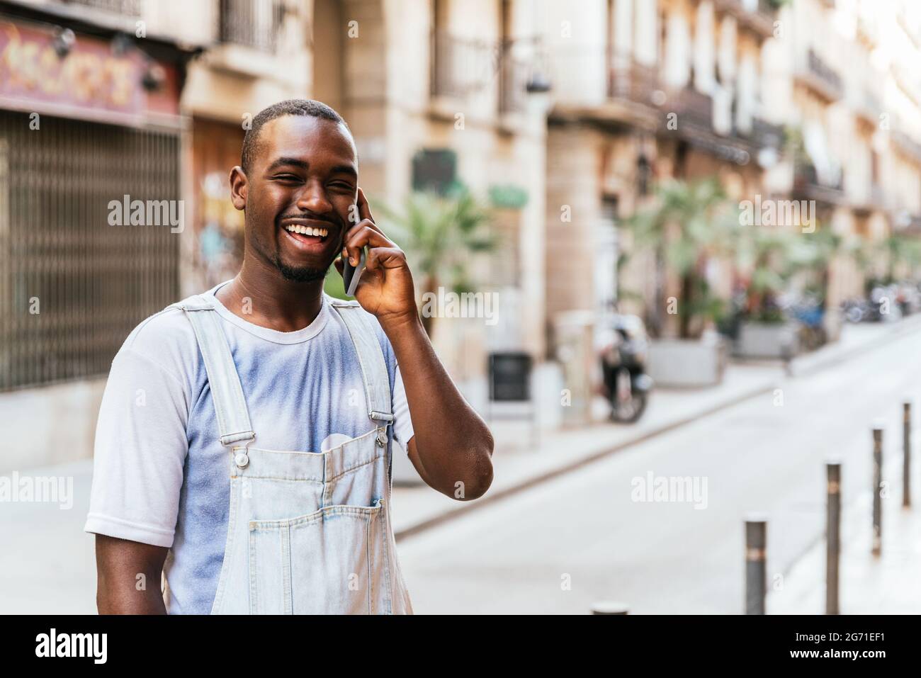 joyeux afro homme souriant et parlant par téléphone. Il s'habille de vêtements d'été décontractés Banque D'Images
