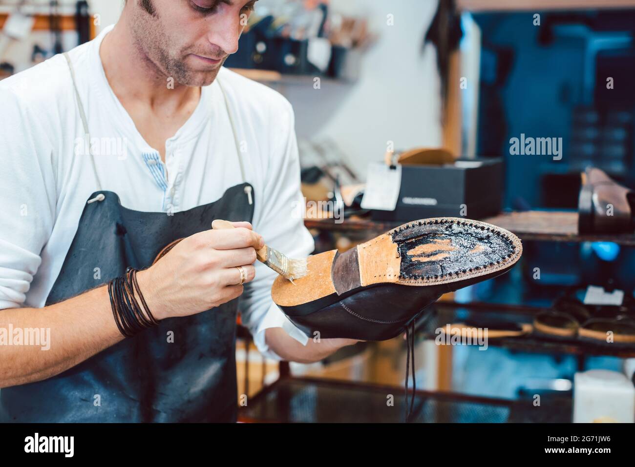 Cordonnier mettant de la colle sur la semelle d'une chaussure à fixer Photo  Stock - Alamy