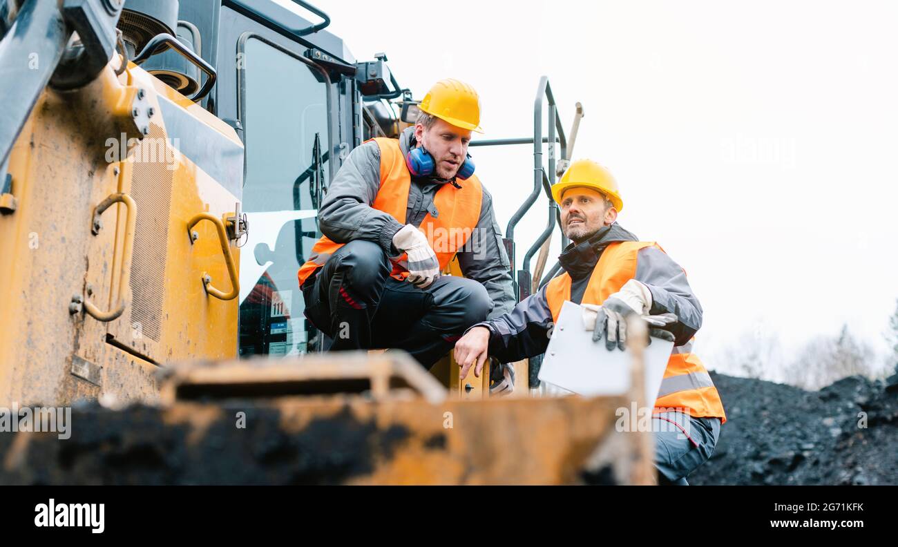 Contremaître montrant le travailleur dans la direction de la fosse minière à ciel ouvert avec ARM étiré Banque D'Images