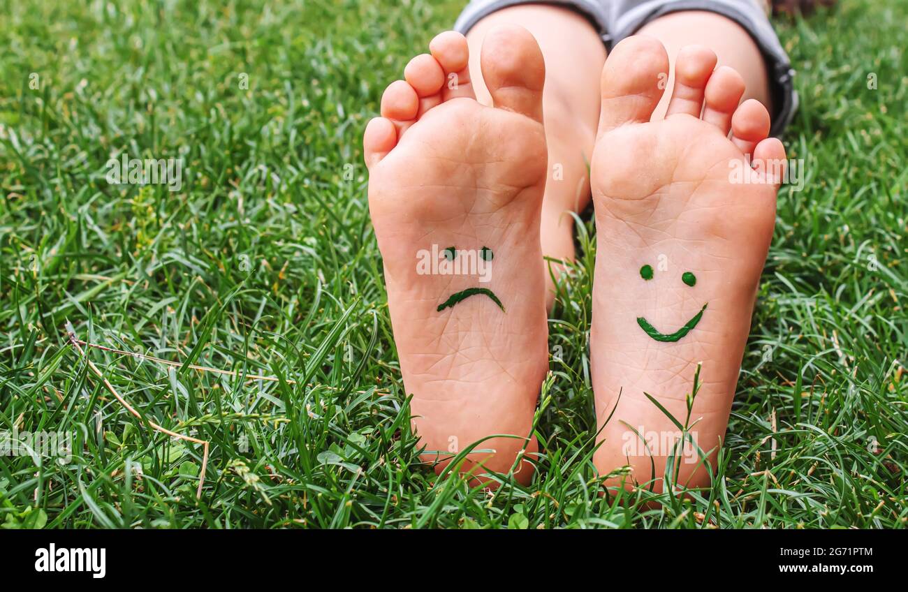 Les Pieds De Bebe Avec Le Motif De Peinture Sont Souriants Et Tristes Sur L Herbe Verte Mise Au Point Selective Photo Stock Alamy