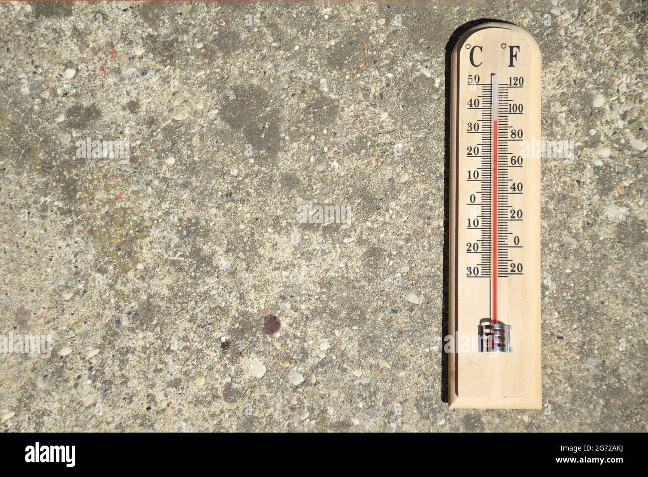 Thermomètre sur fond de béton indiquant une température estivale élevée Banque D'Images