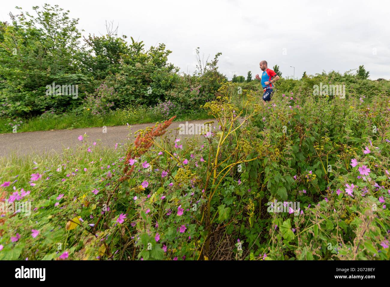 Shoeburyness, Essex, Royaume-Uni. 10 juillet 2021. Reporté en 2020 en raison de la pandémie de COVID-19, le triathlon a été autorisé à revenir car les restrictions sont levées pour 2021. Se tenant dans la zone de Shoeburyness à l'est de Southend on Sea, les concurrents ont commencé la compétition avec une baignade de 750 m dans l'estuaire de la Tamise avant de prendre leurs vélos pour une promenade de 20 km à travers les routes de campagne et de retour pour une course de 5 km dans le Gunners Park côtier avec ses structures défensives imposantes en temps de guerre. L'ancien quartier de MOD est maintenant une réserve naturelle et une zone de marche populaire. Chemin de table mâle traversant les bagues Banque D'Images