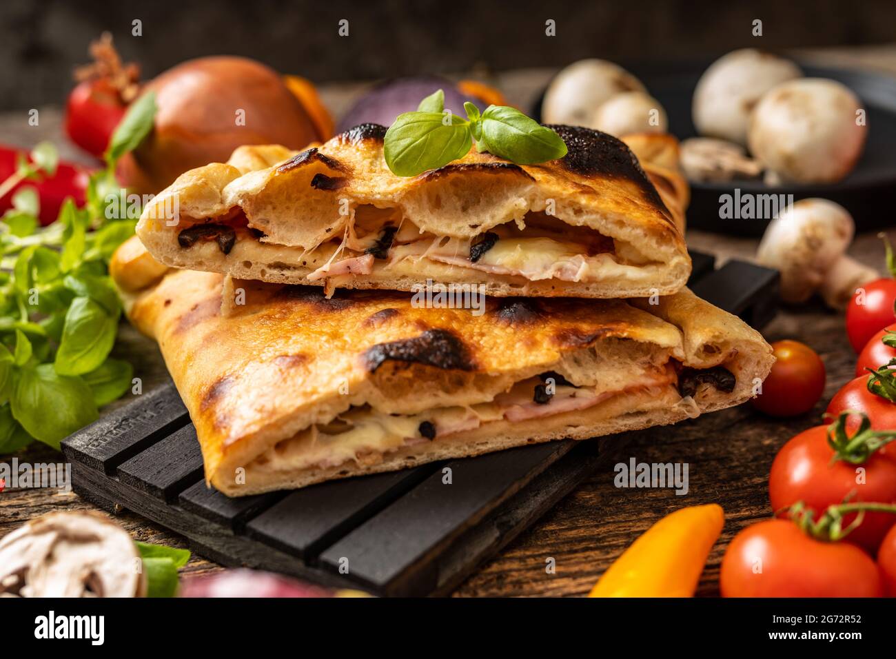 Pizza en tranches calzone servie sur une palette noire Banque D'Images