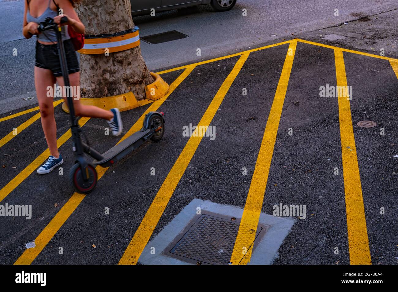 pieds de femme avec scooter électrique dans la ville. bandes jaunes sur l'asphalte Banque D'Images