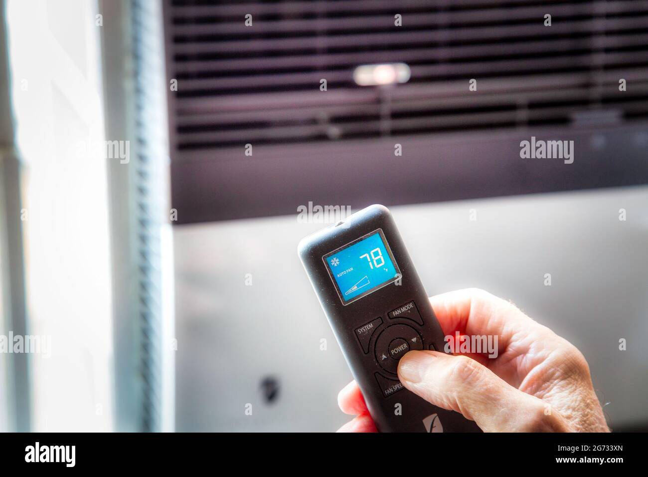 Homme utilisant une télécommande pour contrôler l'unité de climatisation de fenêtre, NYC, Etats-Unis Banque D'Images