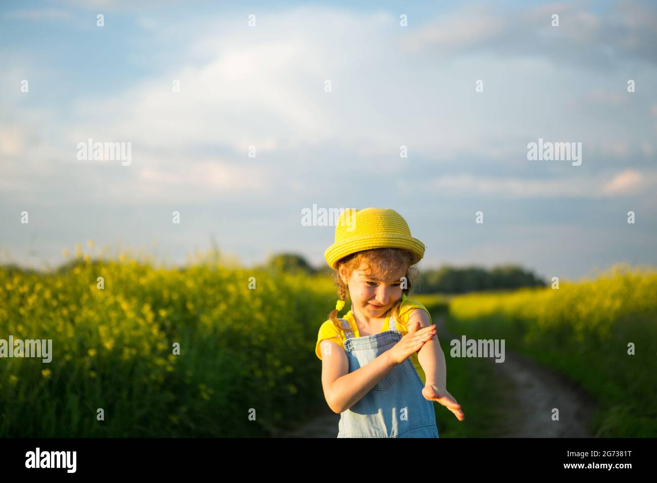 Une fille tue des moustiques sur ses mains et ses pieds. L'enfant se claque sur le corps, égratignure des points de morsure, protection contre les piqûres d'insectes, répulsif sûr pour Banque D'Images