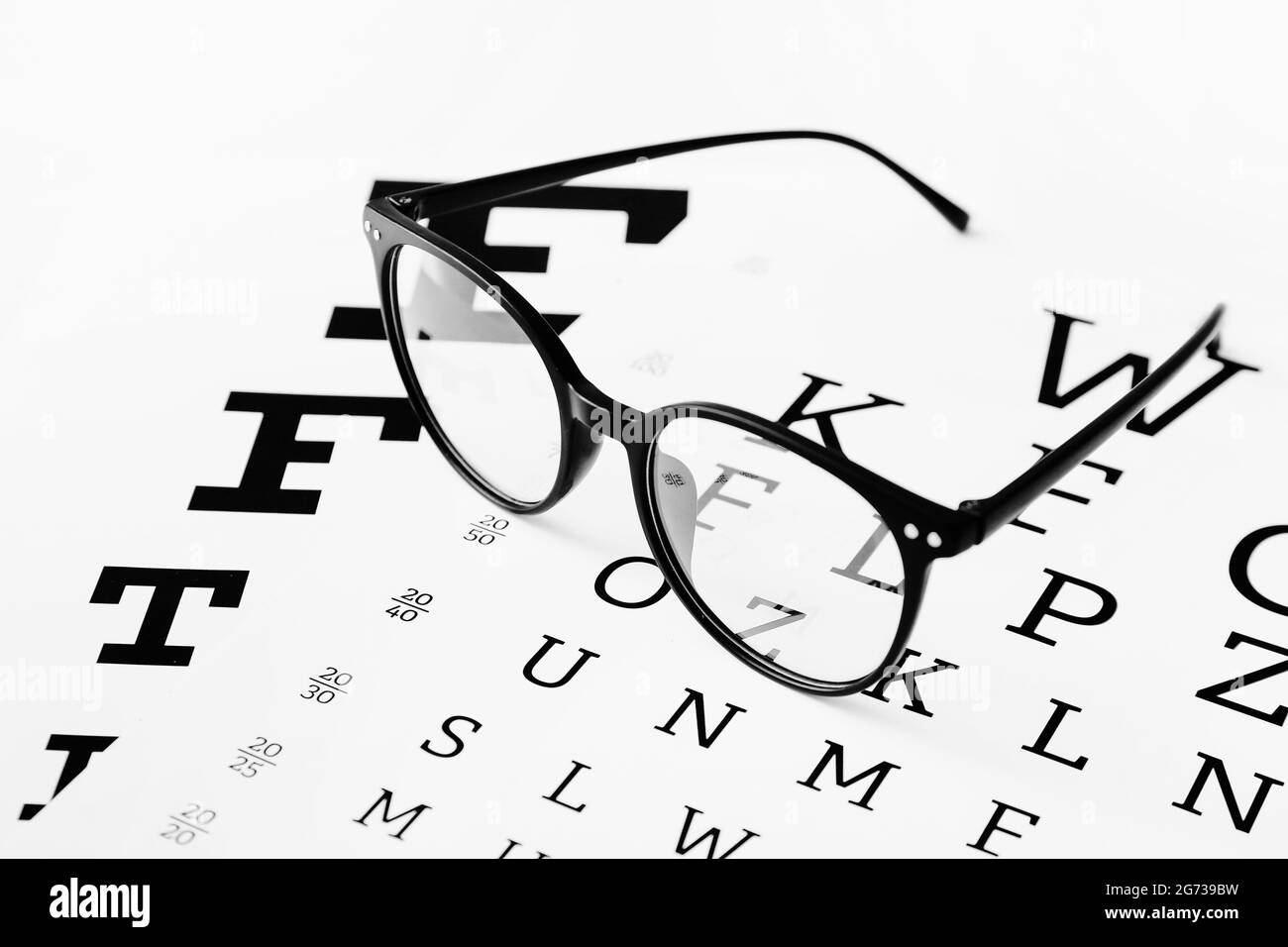 Lunettes élégantes avec graphique de test oculaire sur fond blanc, gros plan Banque D'Images