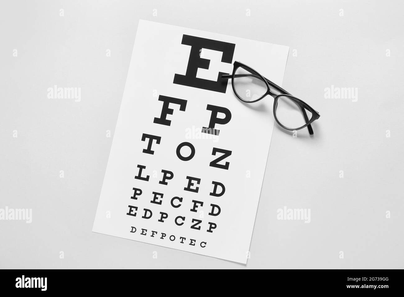 Lunettes élégantes avec tableau de test oculaire sur fond clair Banque D'Images