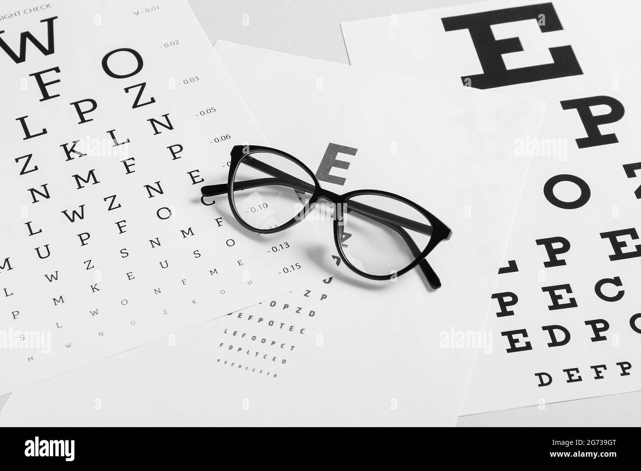 Lunettes élégantes avec cartes de test oculaire sur fond clair Banque D'Images