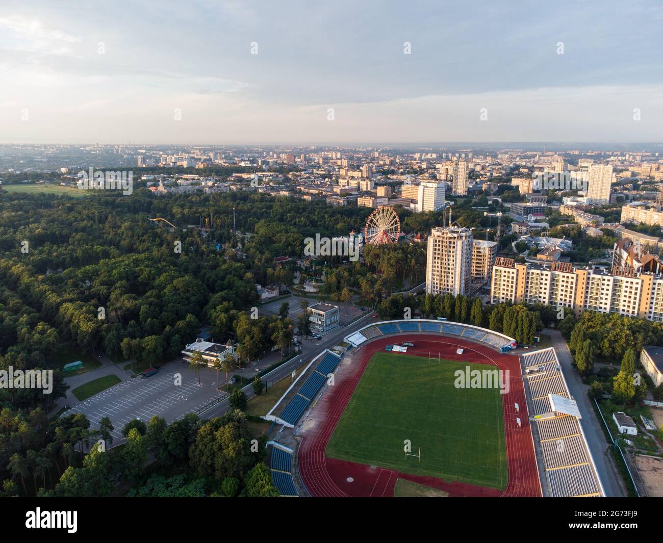 Vue sur le centre-ville de Kharkiv avec parc de Maxim Gorky, stade et bâtiments résidentiels à plusieurs étages avec coucher de soleil pittoresque ciel nuageux en été Banque D'Images