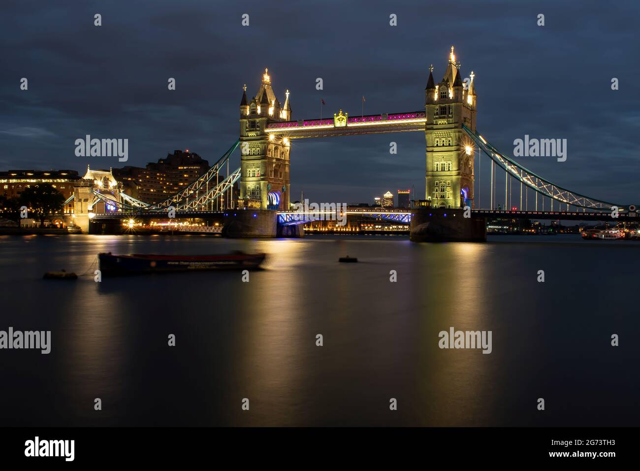 Tower Bridge dans la ville de Londres illuminé en soirée. Les lumières se reflètent sur l'eau de la Tamise. Londres, Angleterre. Banque D'Images