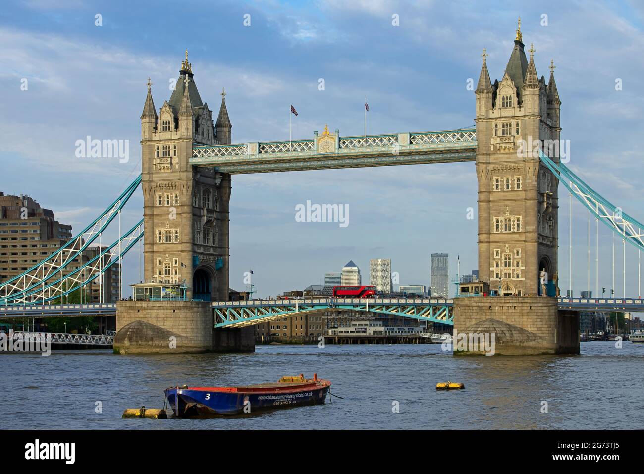 Tower Bridge au soleil de la fin de l'après-midi. Un bus rouge de Londres ferme la section du pont à tirer, avec Canary Wharf visible en bas de la rivière. Londres, Angleterre Banque D'Images