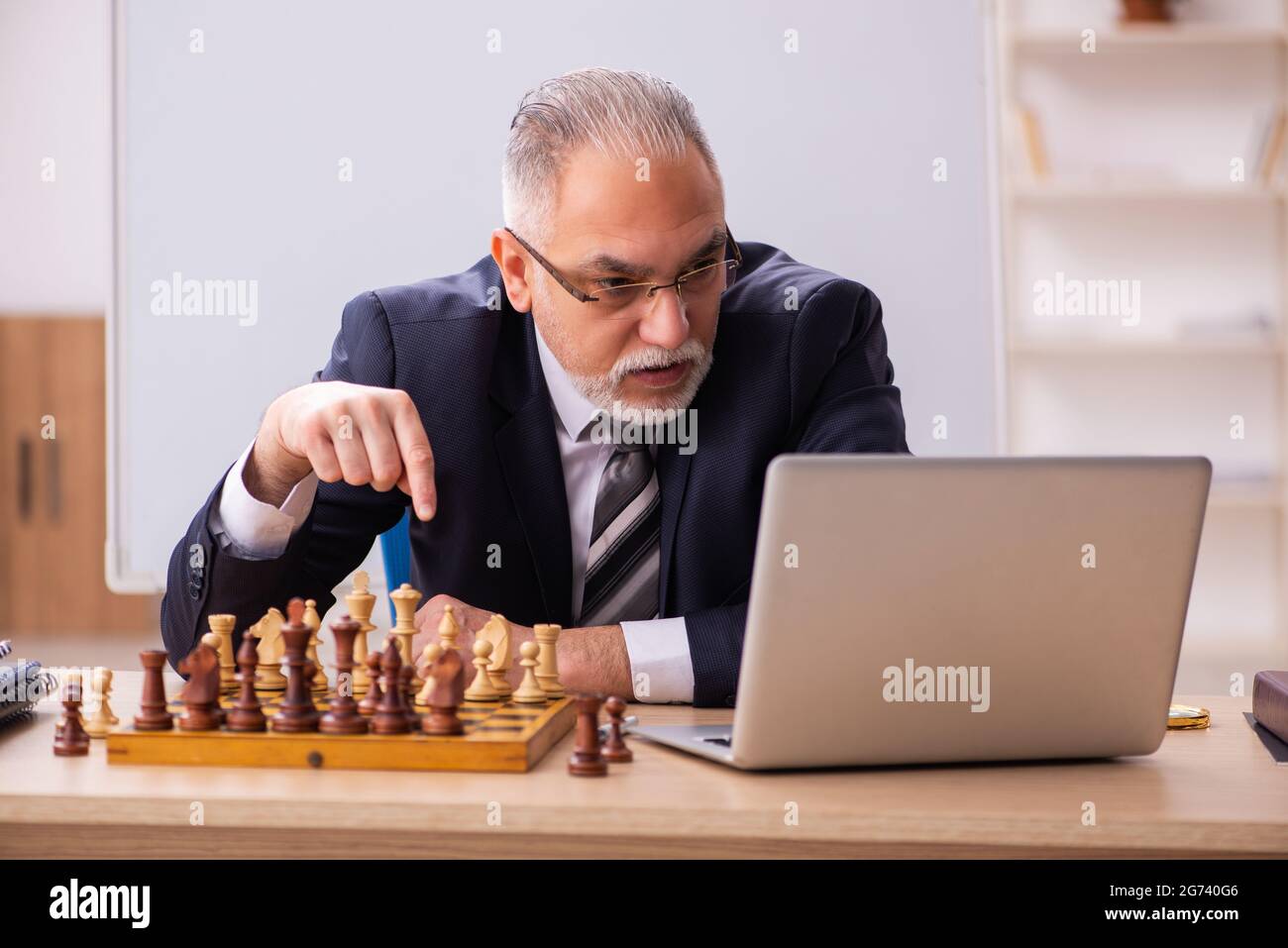 Un vieux employé d'homme d'affaires jouant aux échecs sur le lieu de travail Banque D'Images