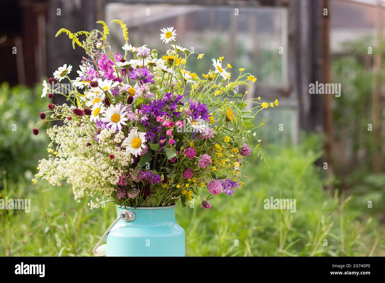 Bouquet de fleurs sauvages brillantes en boîte vase sur table à l'extérieur, scène rurale. Modèle de carte postale. Concept Fête des femmes, Fête des mères, Bonjour été ou Banque D'Images