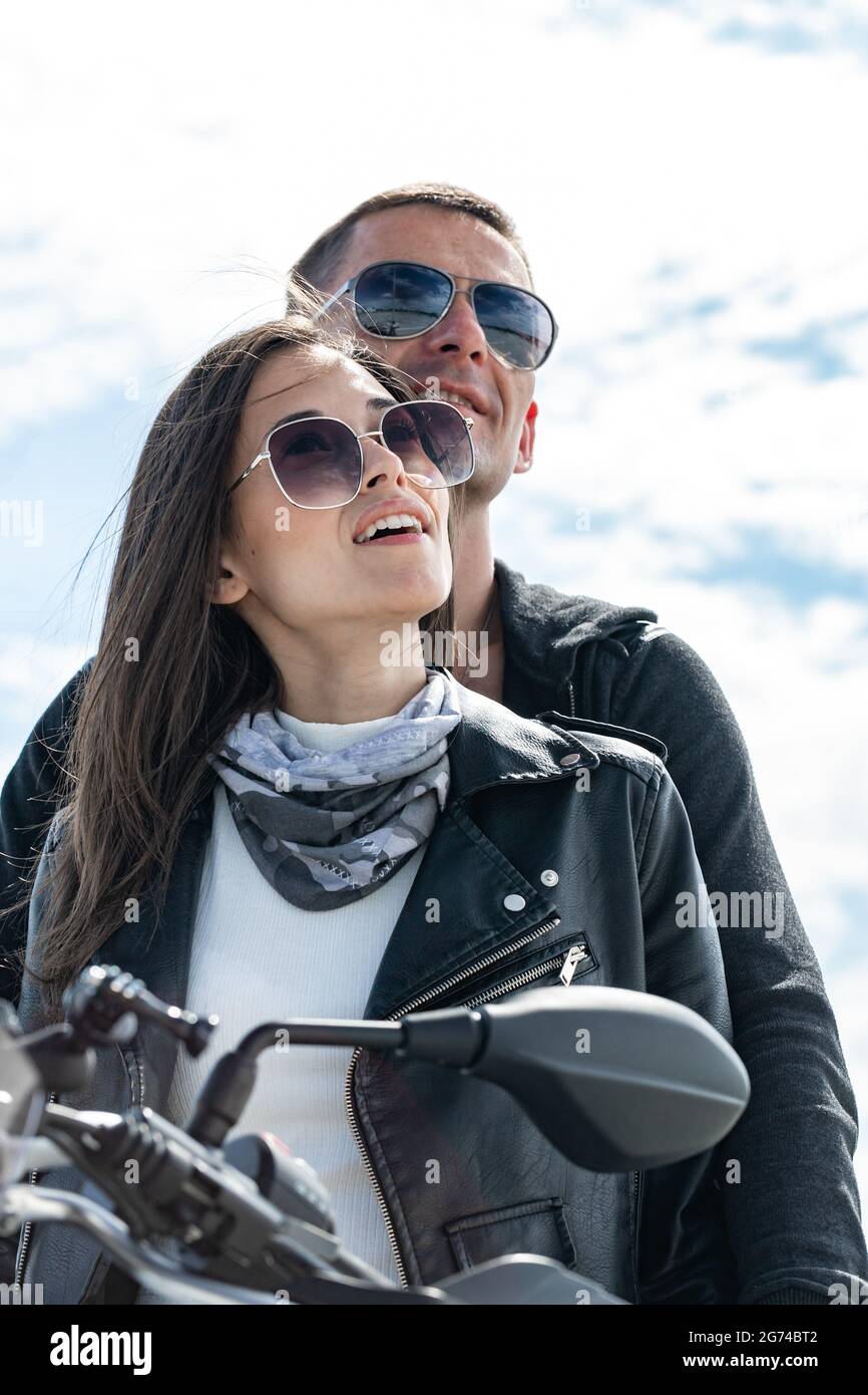 Beau gars et belle fille en lunettes de soleil. Un couple de jeunes motards souriants heureux. Deux caucasiens sont assis sur la moto. SH. Vertical Banque D'Images