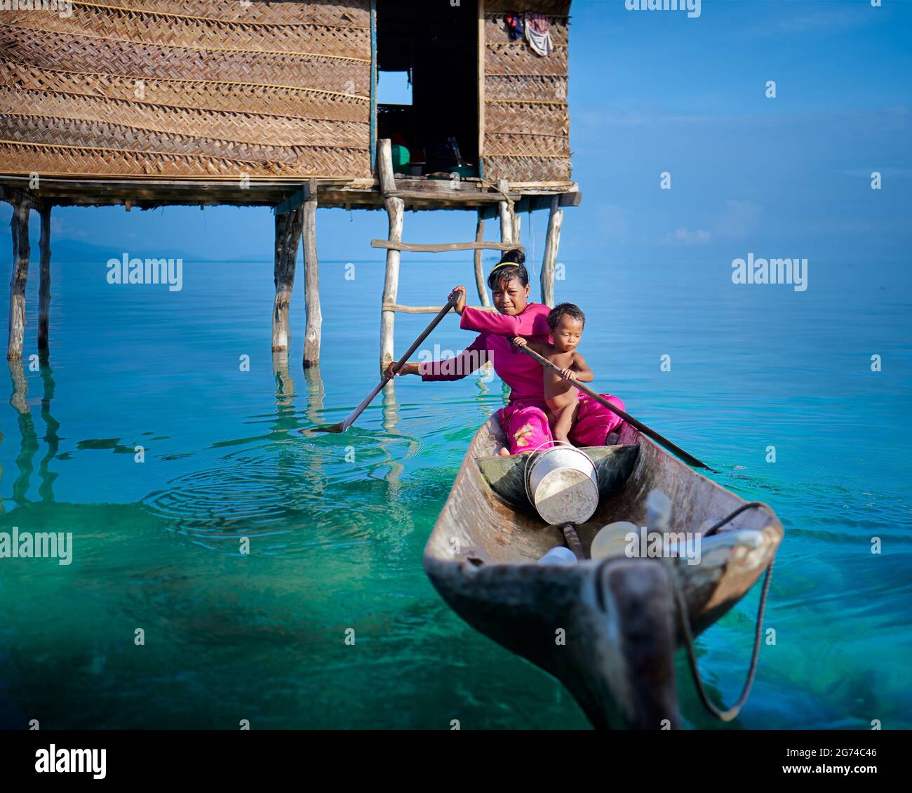 Une mère et un fils Bajau quittant leur pilotis à la maison sur un bateau en bois Banque D'Images