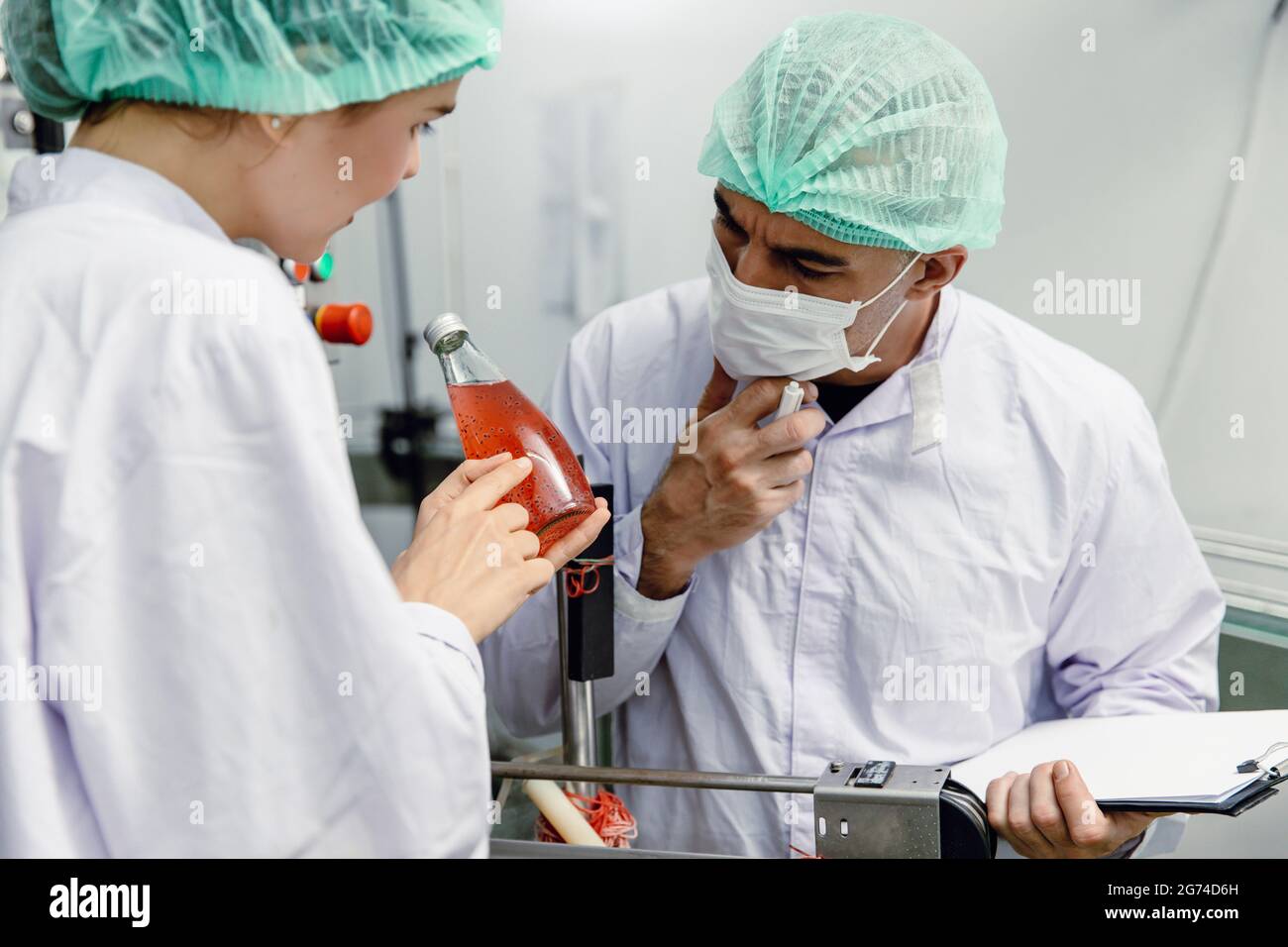 Équipe de travail spécialisée qui vérifie le produit bouteille de boisson contamine la qualité de nettoyage en usine. Travail d'équipe personnes de haut niveau dans l'industrie alimentaire concept. Banque D'Images