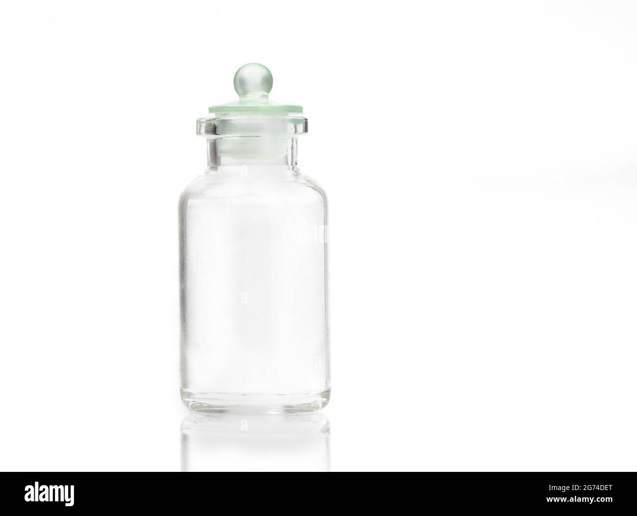 Petit récipient en verre avec lumière vive sur fond blanc. Banque D'Images