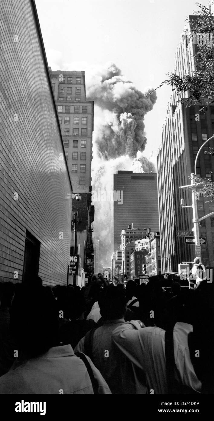 ÉTATS-UNIS. NYC. 9/11/2001. Les piétons courent des débris qui tombent alors que la deuxième tour du World Trade Center s'effondre après une attaque terroriste. Banque D'Images