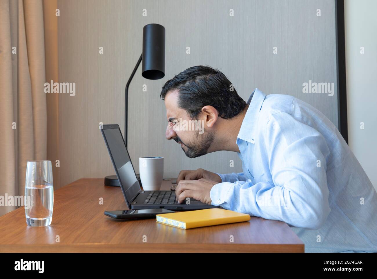 Homme avec une mauvaise vue travaillant dans son ordinateur portable, luttant pour voir Banque D'Images