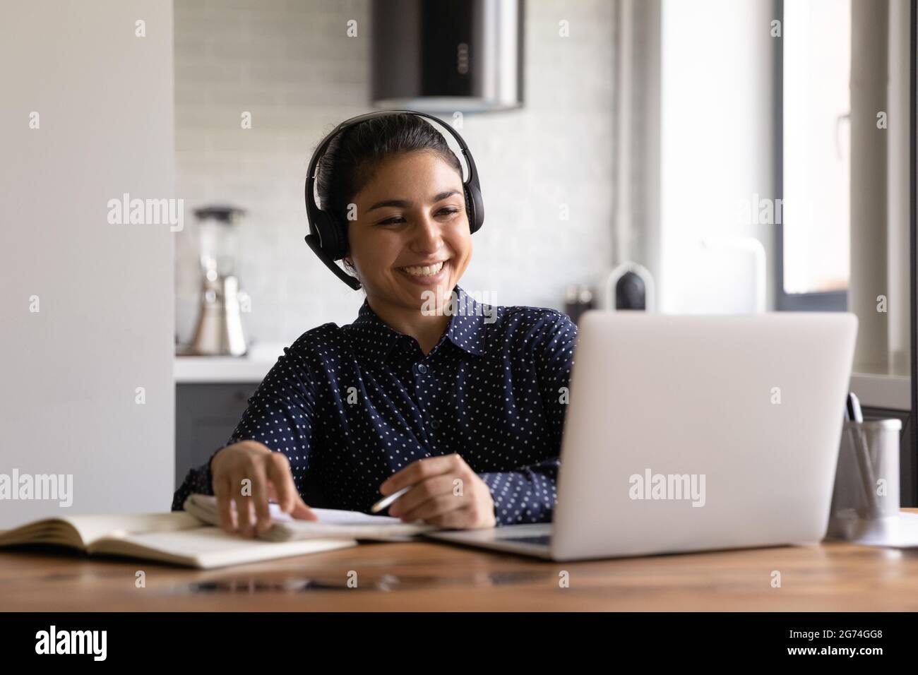Joyeux étudiant indien dans un casque avec microphone pour assister à une formation virtuelle Banque D'Images