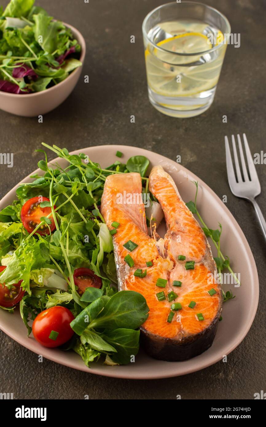 Un délicieux déjeuner copieux, un morceau de steak de truite frit et un mélange de différents types de salade verte, dîner avec du poisson rouge sain Banque D'Images