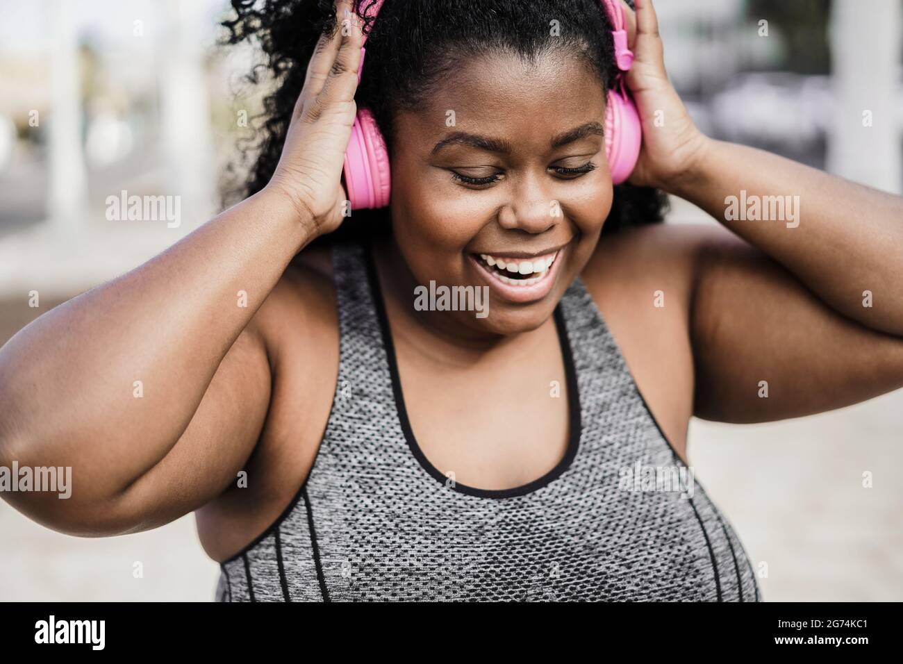 Happy sport femme noir et courbes écoutant de la musique avec un casque - Focus on face Banque D'Images