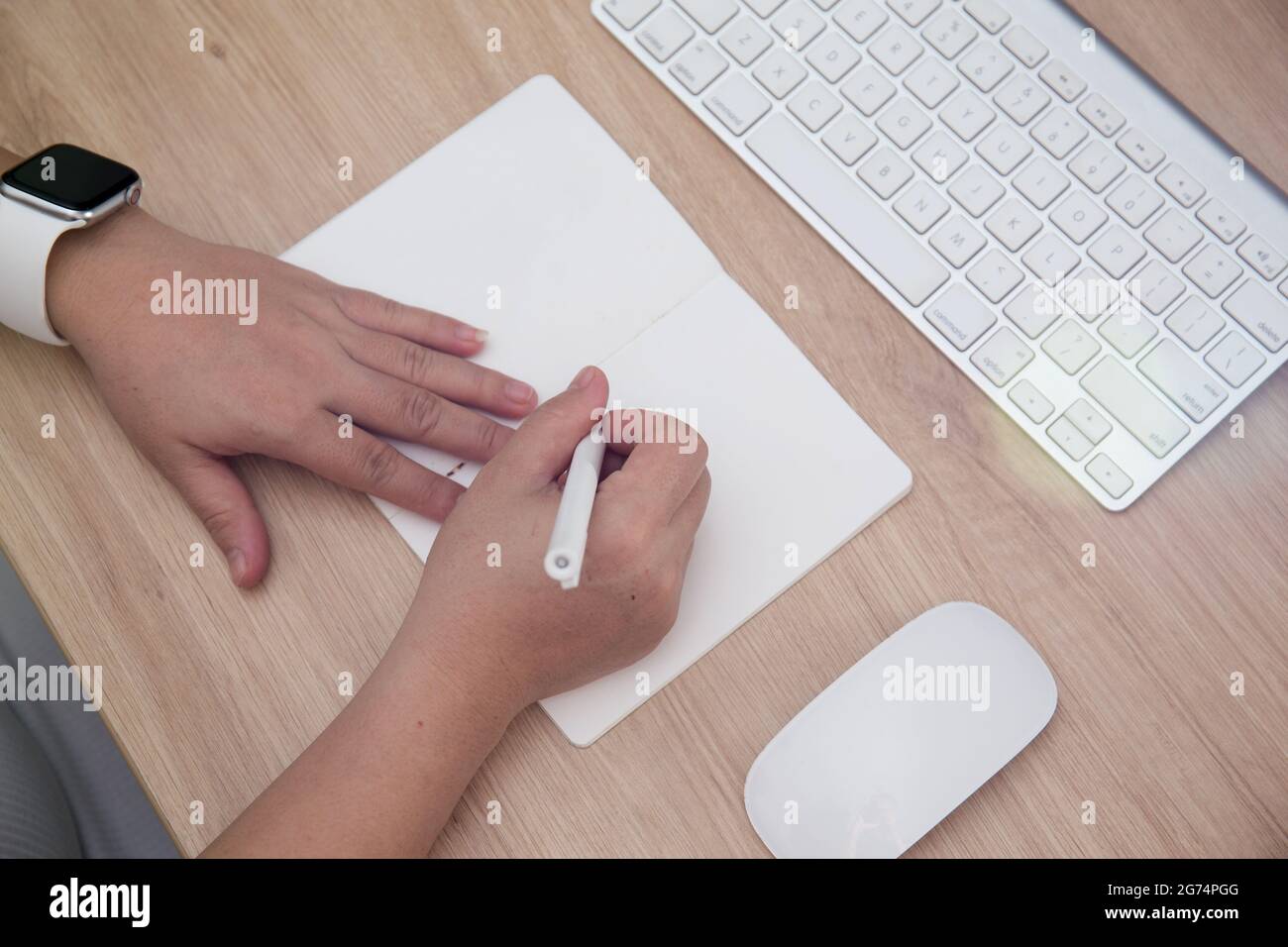 Un coup de tête de mains de femmes écrivant dans un carnet et un clavier sur la table Banque D'Images