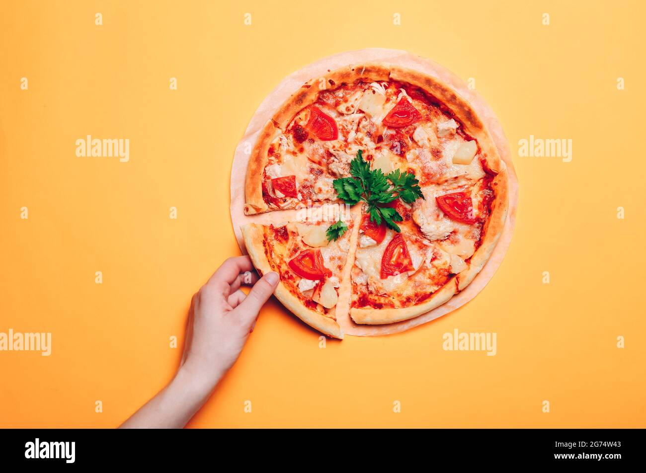 Une femme prend une tranche de pizza, sur un fond orange sans couture. Vue de dessus Banque D'Images