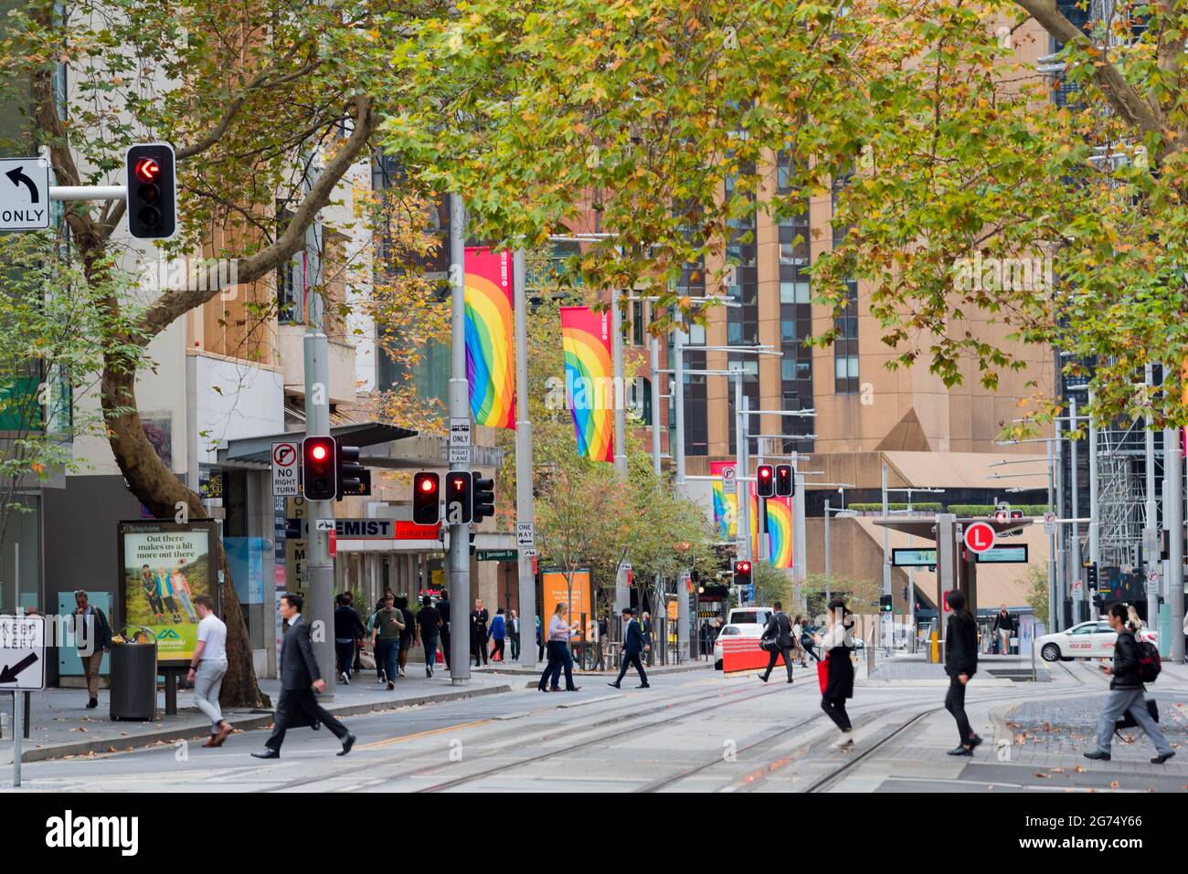 La plupart du temps dépourvus de voitures et d'autobus, les piétons traversent les lignes de tramway de George Street et les drapeaux arc-en-ciel volent depuis les poteaux de Sydney, Nouvelle-Galles du Sud. Banque D'Images