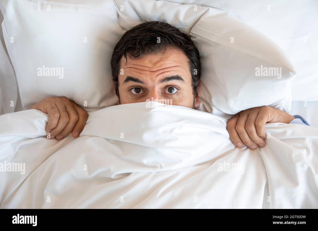 homme moyen agem dans le lit , se cachant sous les couvertures Banque D'Images