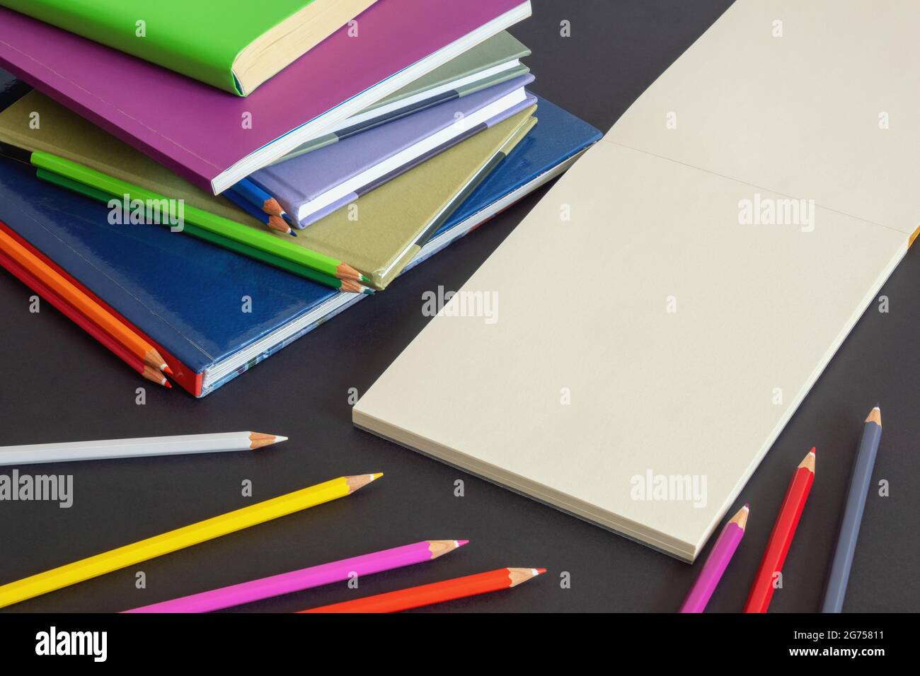 Concept scolaire. Pile de livres, crayons colorés et croquis ouverts sur fond de papier foncé. Espace libre pour le texte ou l'image Banque D'Images