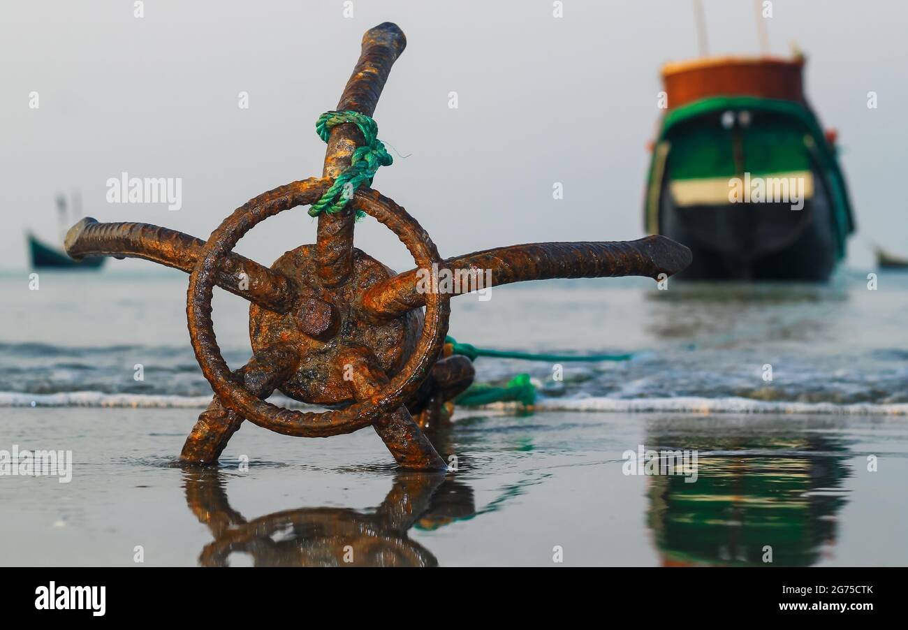 Un bateau de pêche ancré sur la plage de l'île Saint-Martin, au Bangladesh. Bateau de pêche rouillé ancre traditionnelle sur une plage au bord de la mer. Ancrage rouillé. Banque D'Images
