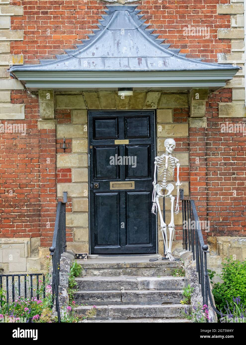 Squelette humain pleine grandeur debout au sommet des marches devant une porte en bois à Cathedral Close, Salisbury, Wiltshire, Royaume-Uni, le 11 juillet 2021 Banque D'Images