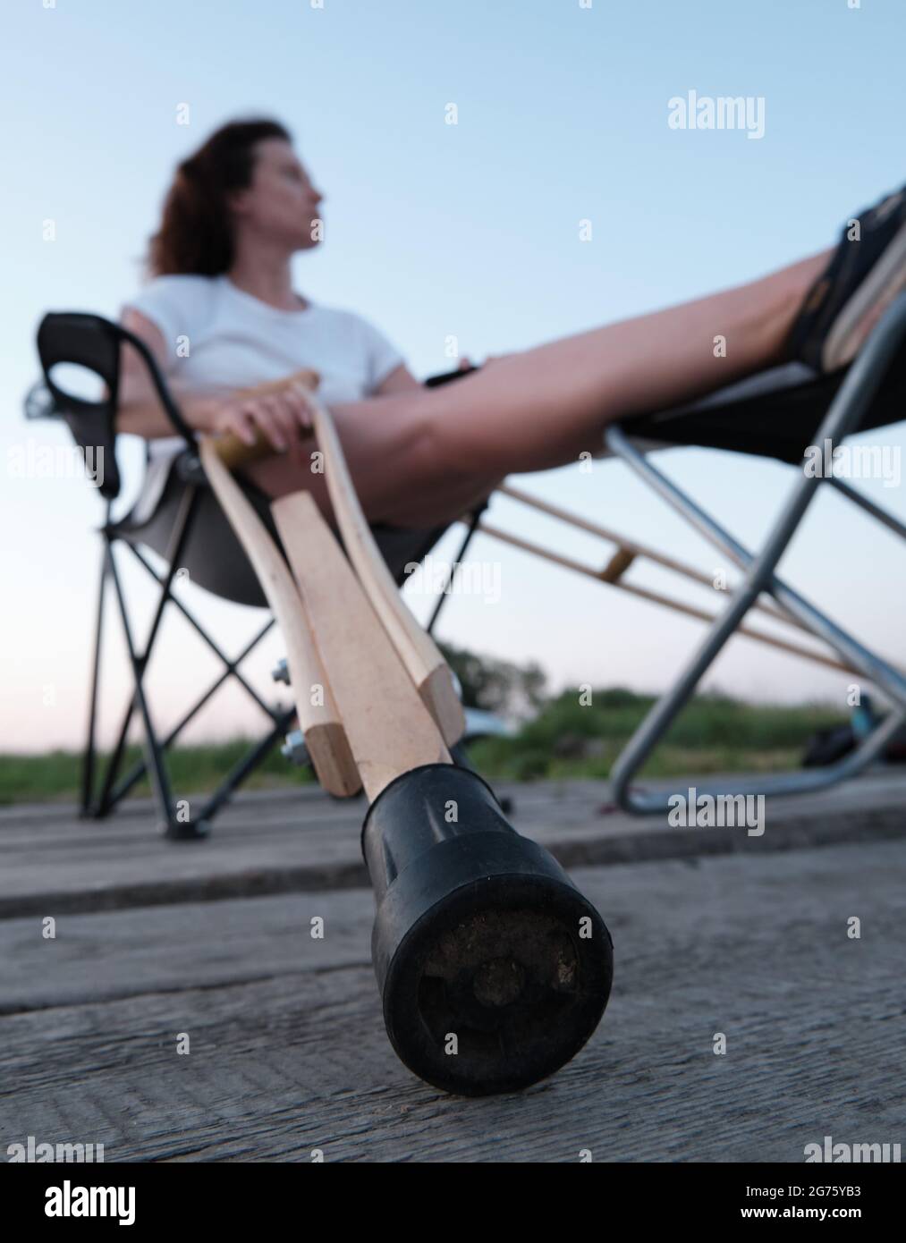 Femme avec cassé en fonte est assise sur une chaise dans la nature. Blessures aux jambes. Perte de mobilité. Réadaptation après une fracture. Banque D'Images