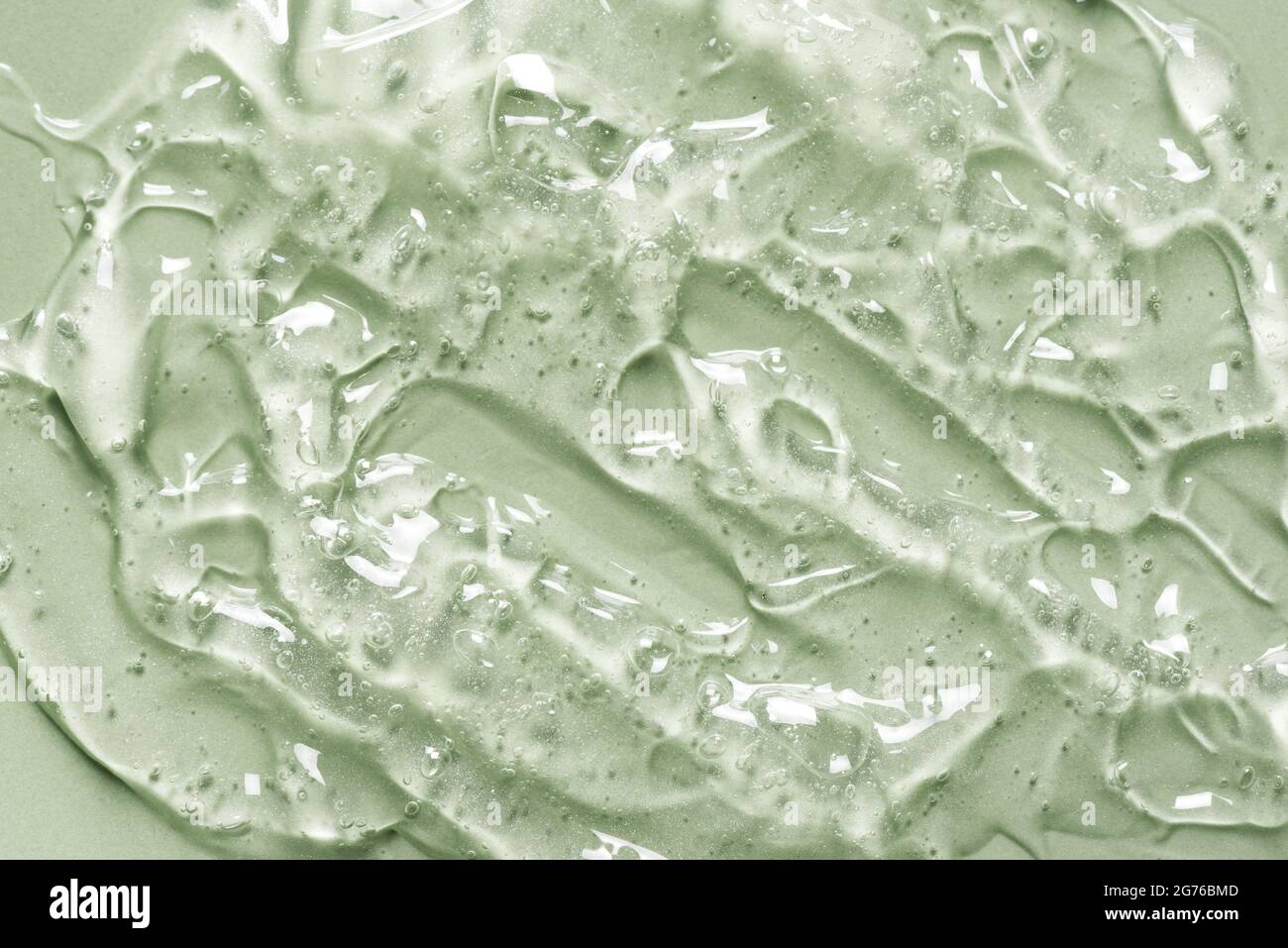 Texture gel sur fond vert gros plan. Produit cosmétique en gel transparent soupiré. Banque D'Images