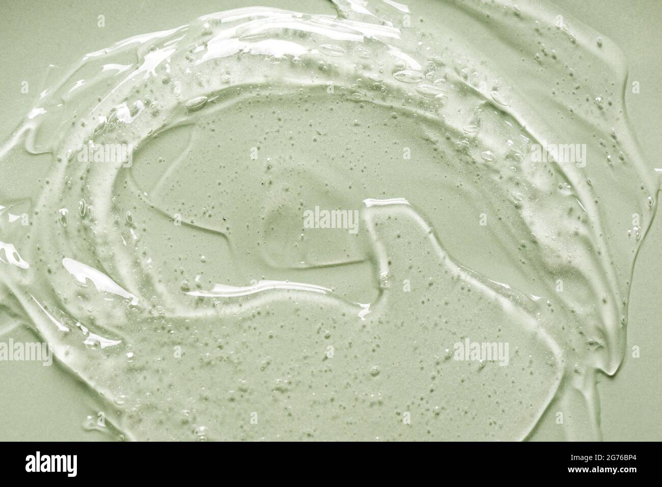 Texture gel sur fond vert gros plan. Tourbillon de gel transparent produit cosmétique. Banque D'Images