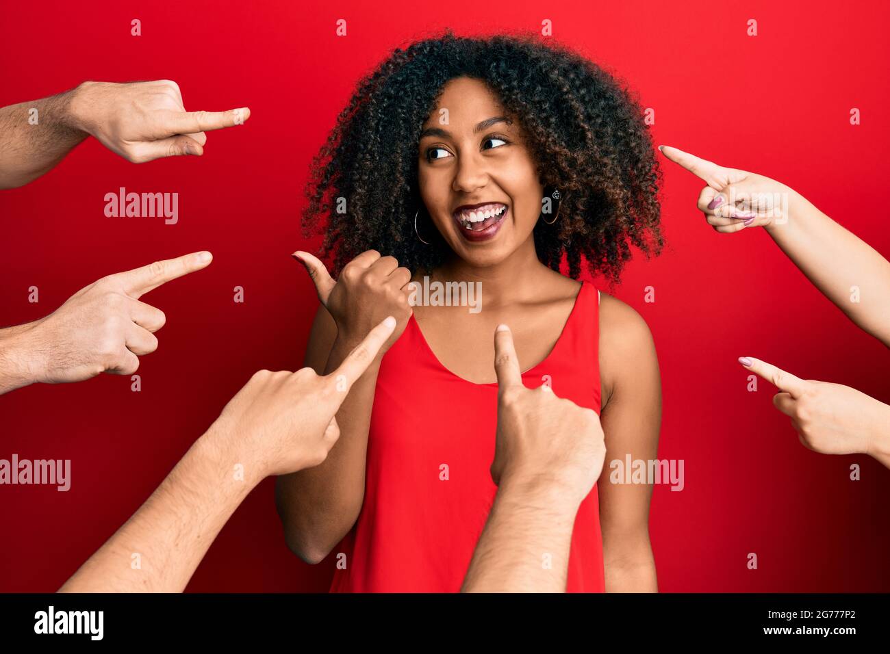 Belle femme afro-américaine avec les cheveux afro-américains avec les doigts autour de pointer vers elle-même pointant le pouce vers le côté souriant heureux avec la bouche ouverte Banque D'Images