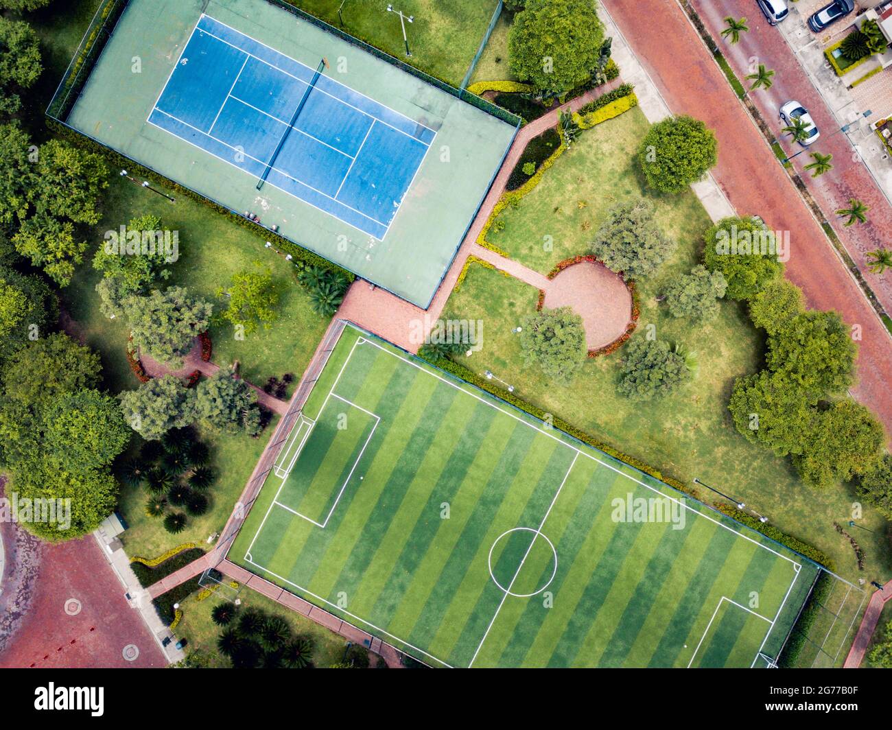 Un tir de drone de terrain de mini-football vide et un terrain de ténis entouré d'un parc et d'arbres dans une communauté fermée à l'extérieur de Guayaquil City, en Équateur. Banque D'Images