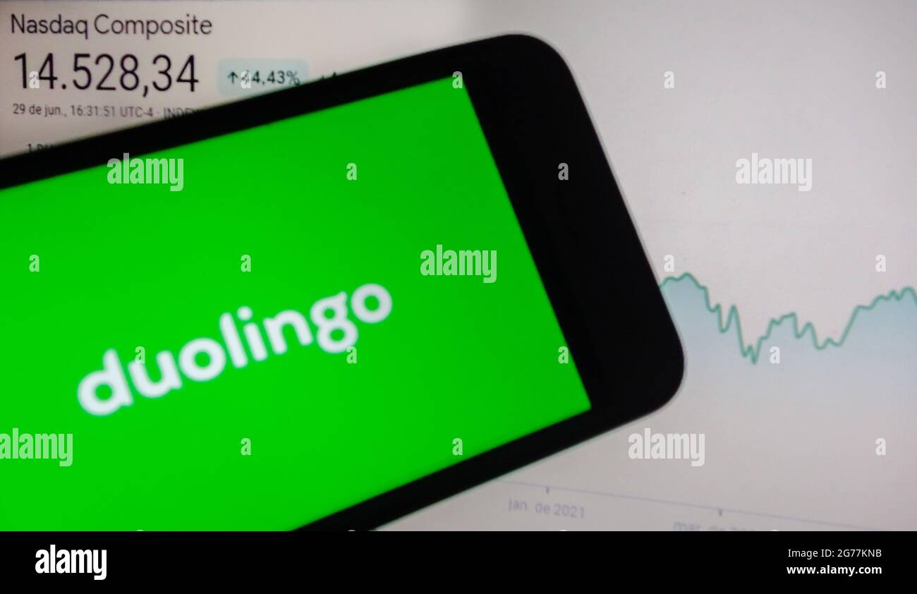 SAO PAULO, BRÉSIL - 01 mai 2021 : smartphone avec logo de l'application en langue Duolingo à l'écran et arrière-plan flou avec le site de bourse Nasdaq. Duol Banque D'Images