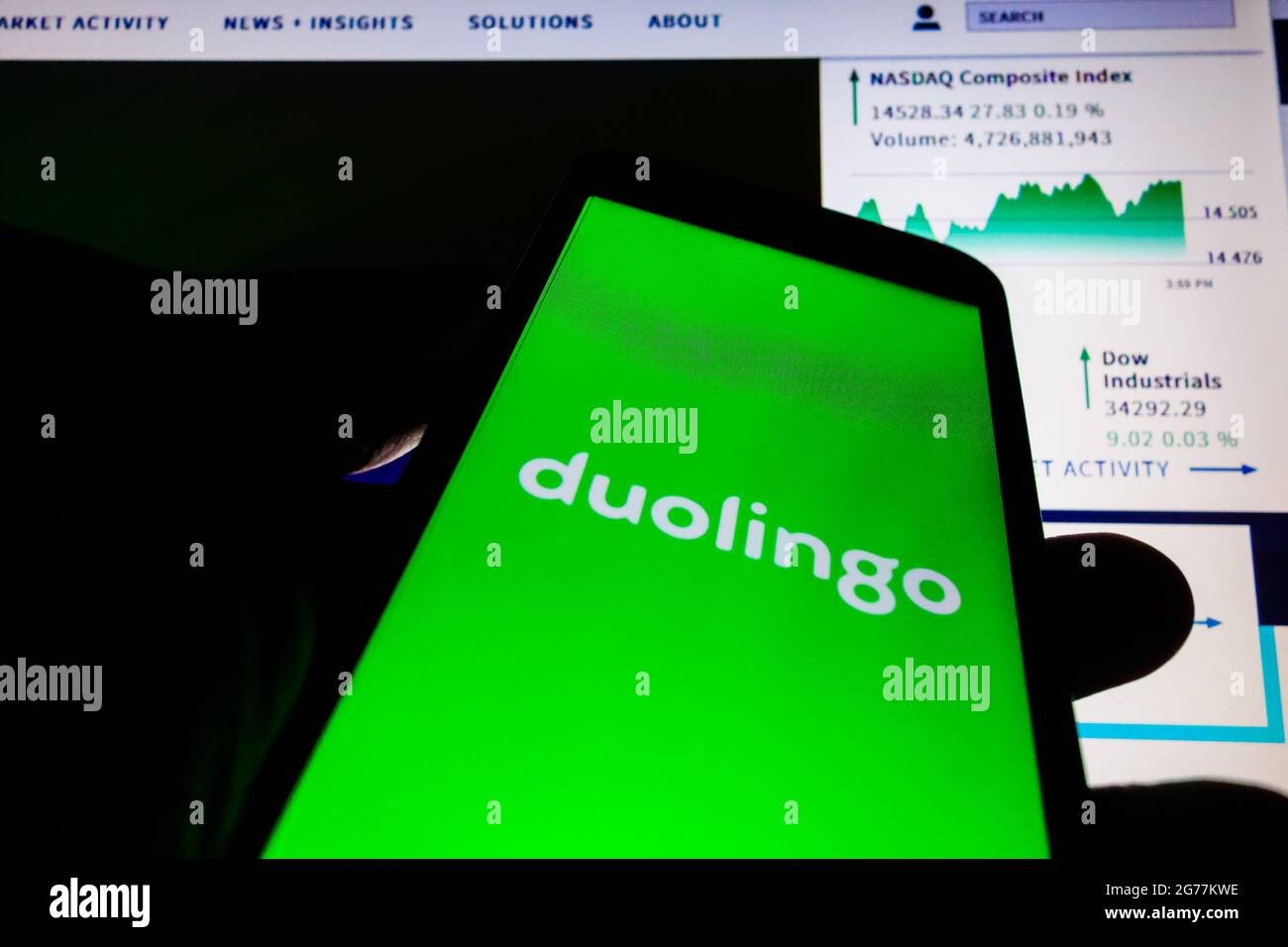 SAO PAULO, BRÉSIL - 01 mai 2021 : smartphone avec logo de l'application en langue Duolingo à l'écran et arrière-plan flou avec le site de bourse Nasdaq. Duol Banque D'Images