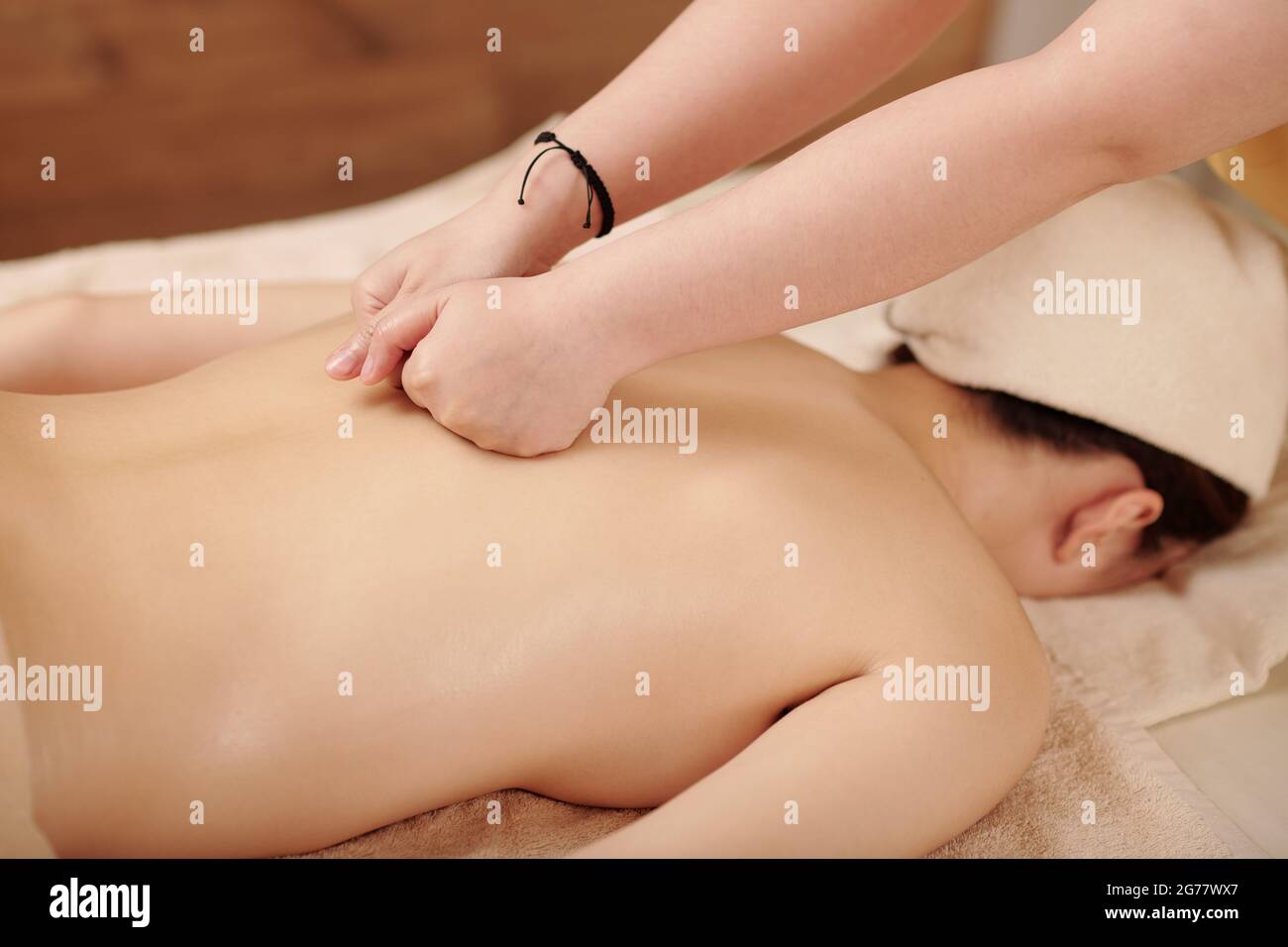 Image rapprochée d'un thérapeute qui donne un massage des tissus profonds avec des poings à une jeune femme Banque D'Images