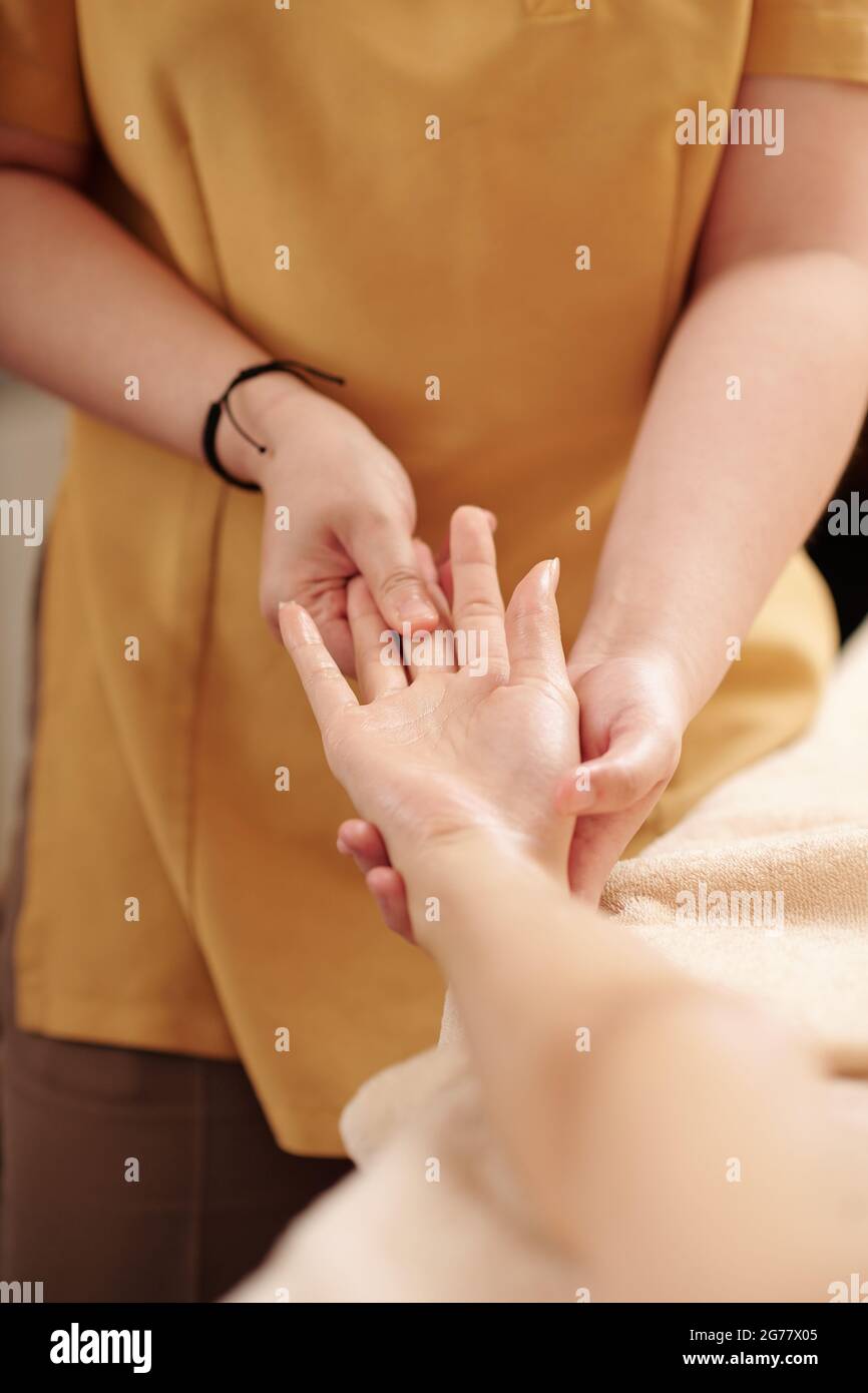 Image en gros plan de la femme thérapeute appuyant des taches spécifiques sur la paume de la jeune femme Banque D'Images