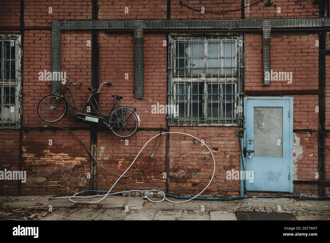 Porte bleue dans un mur en brique rouge d'un bâtiment à colombages avec vélo tandem accroché au mur des quais de Gdansk Banque D'Images