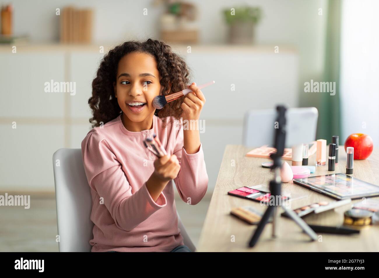 Blog de beauté. Joyeux african american teen enregistrement cosmétique examen de produit, en utilisant le téléphone sur trépied Banque D'Images