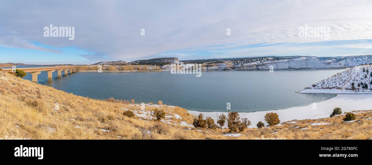 Un lac clair et paisible avec de la neige au bord et un pont sur le côté Banque D'Images
